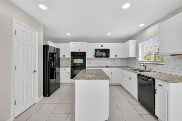 a open kitchen with stainless steel appliances granite countertop a refrigerator and a sink