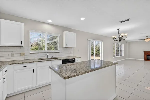 a kitchen with granite countertop a sink white cabinets and window