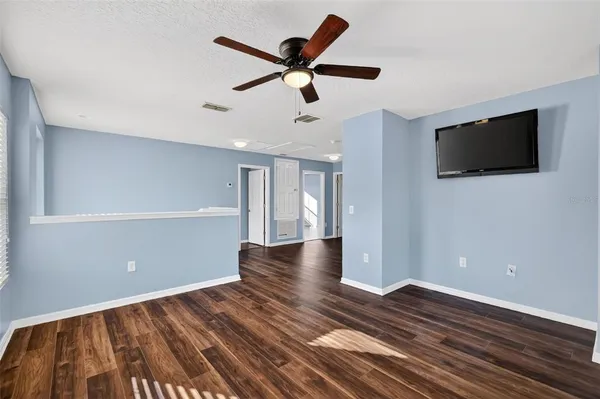 a view of empty room with wooden floor and fan