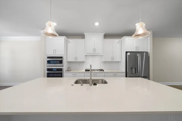 a kitchen with kitchen island a stove a refrigerator and a sink
