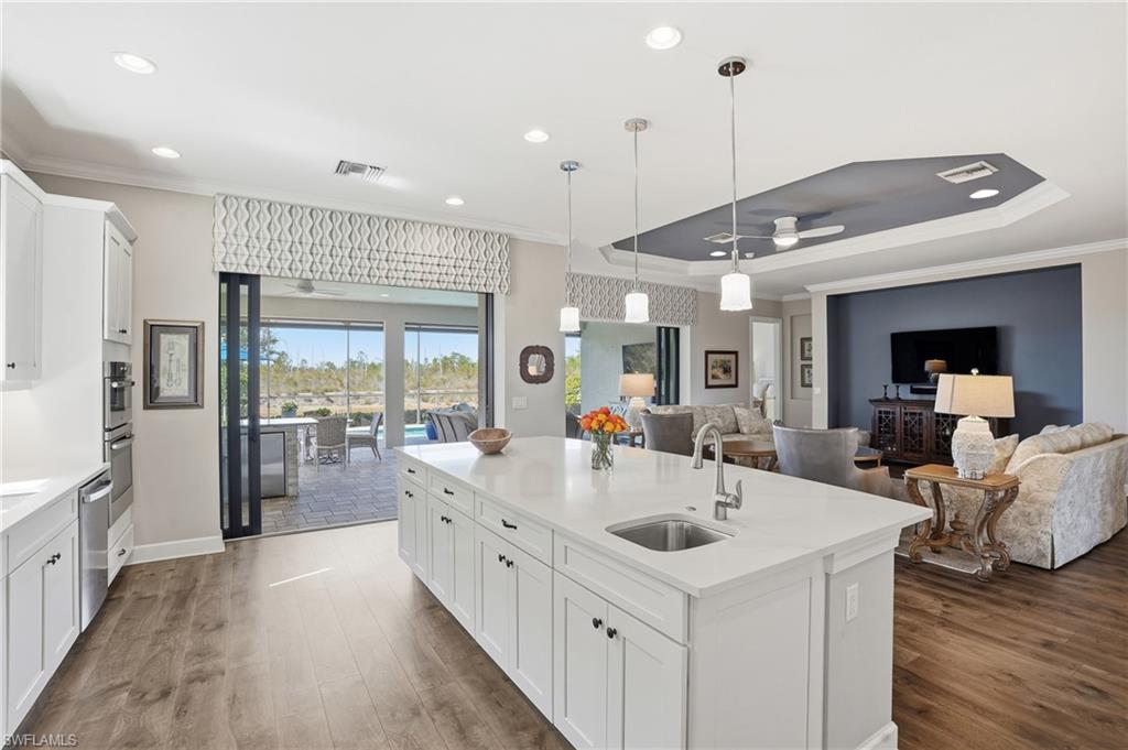 9489 Montelanico Loop Naples, FL 34119 - Photo 48 of 49 Kitchen with white cabinetry, open floor plan, ceiling fan, ornamental molding, and decorative light fixtures