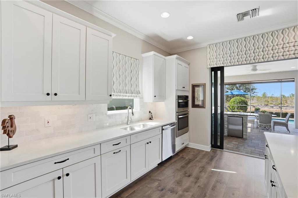 9489 Montelanico Loop Naples, FL 34119 - Photo 13 of 49 Kitchen with white cabinets, dark wood-type flooring, appliances with stainless steel finishes, healthy amount of natural light, and ornamental molding
