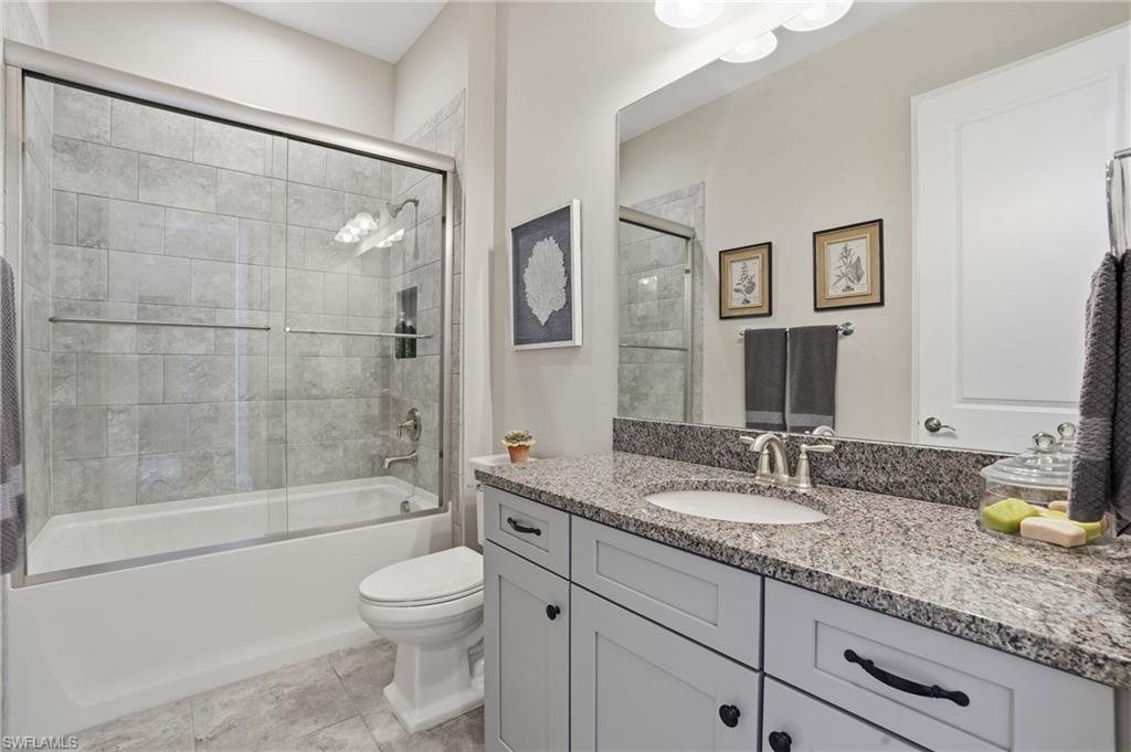 9489 Montelanico Loop Naples, FL 34119 - Photo 25 of 49 Bathroom featuring vanity and bath / shower combo with glass door