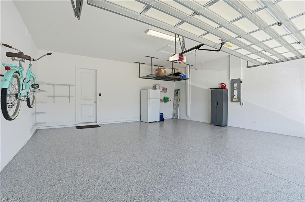 9489 Montelanico Loop Naples, FL 34119 - Photo 28 of 49 Garage with freestanding refrigerator, electric panel, and a garage door opener