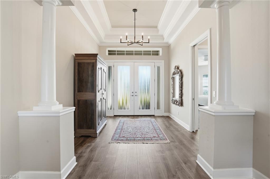 9489 Montelanico Loop Naples, FL 34119 - Photo 5 of 49 Foyer featuring ornate columns, crown molding, wood finished floors, a raised ceiling, and french doors