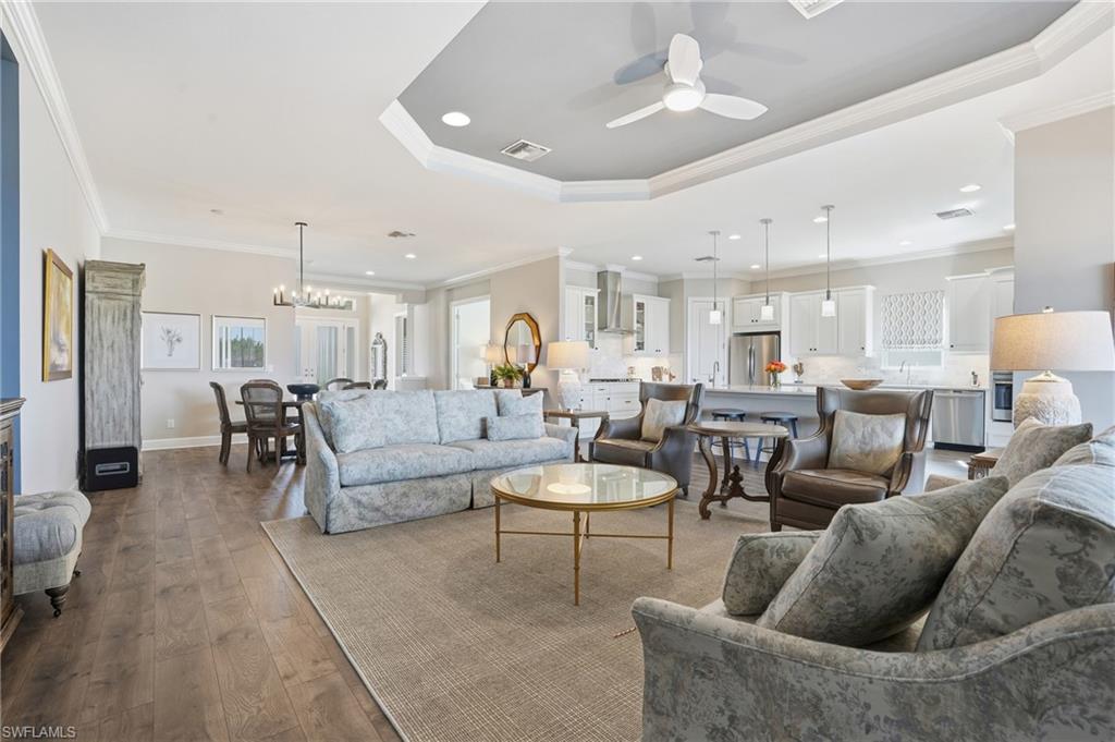 9489 Montelanico Loop Naples, FL 34119 - Photo 8 of 49 Living room with a ceiling fan, recessed lighting, wood-type flooring, crown molding, and a chandelier