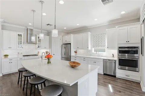 a kitchen with stainless steel appliances a dining table chairs stove refrigerator and cabinets