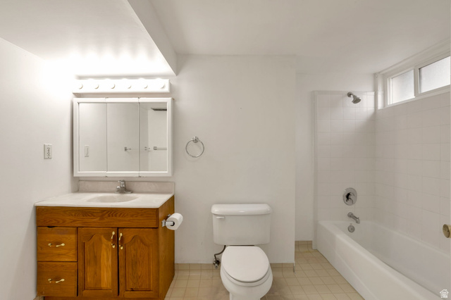 447 550 South Bountiful, UT 84010 - Photo 13 of 25 Bathroom featuring a wood-finish vanity with a built-in sink, a wall-mounted medicine cabinet with integrated mirror, and a full bathtub with a tiled shower surround