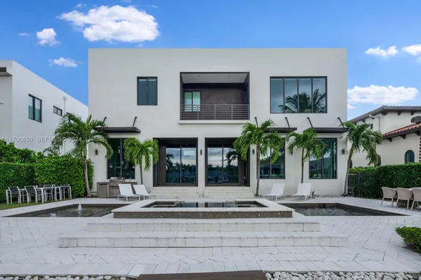 a view of a house with potted plants and palm trees