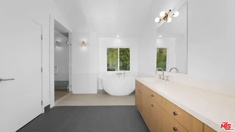 a bathroom with a double vanity sink a window and a bathtub