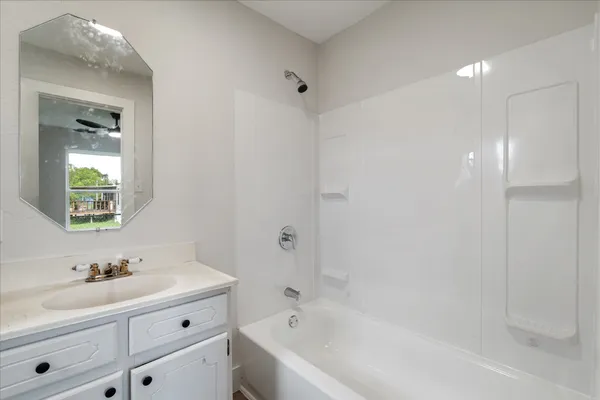 a bathroom with a bathtub shower sink vanity and mirror