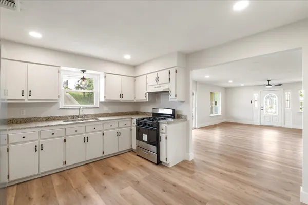 a large kitchen with granite countertop a stove and a sink