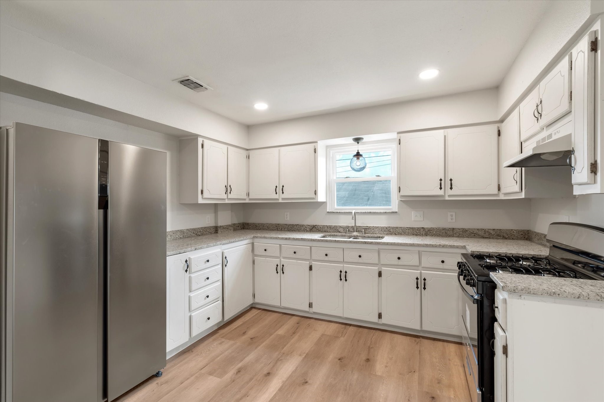 7104 Dallas Street, Unit 1 Baytown, TX 77521 - Photo 6 of 17 a kitchen with granite countertop white cabinets white stainless steel appliances and wooden floors