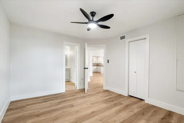 a view of empty room with wooden floor and ceiling fan