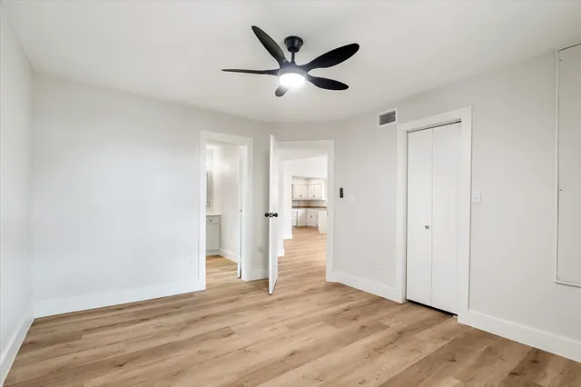 a view of empty room with wooden floor and ceiling fan
