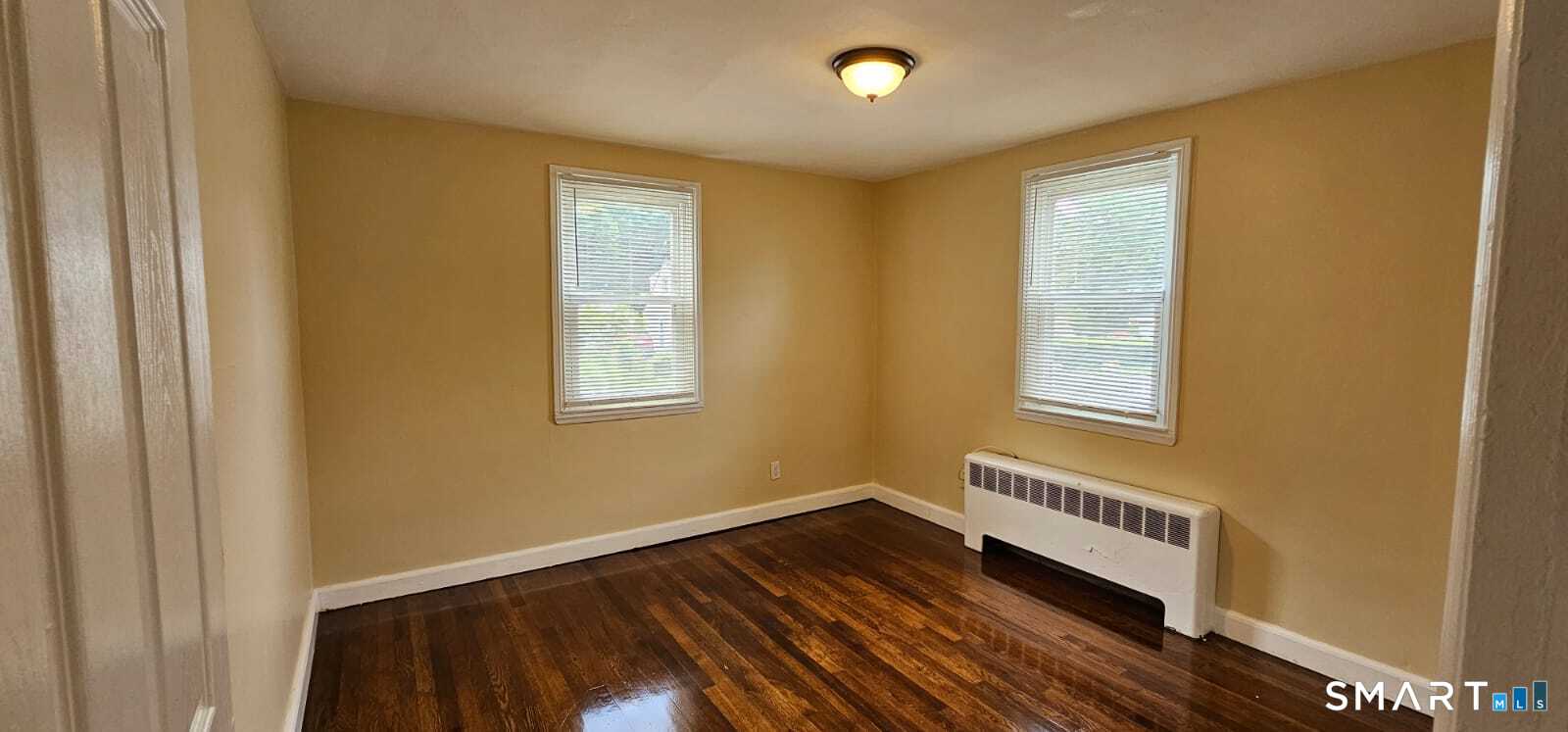 98 East Burnham Street Bloomfield, CT 06002 - Photo 3 of 18 a view of an empty room with wooden floor and a window