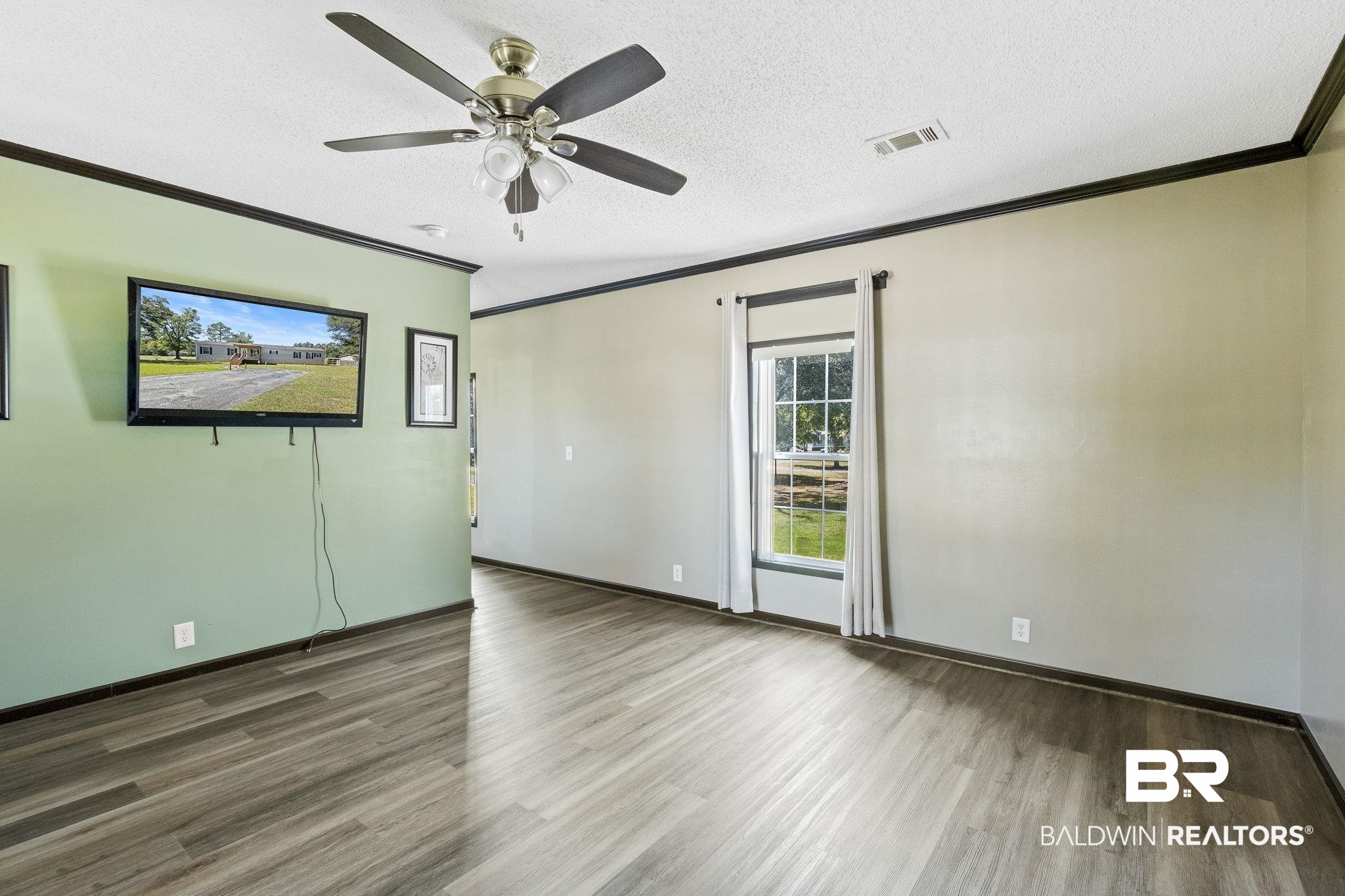 6870 Cecilia Court Theodore, AL 36582 - Photo 13 of 83 Empty room featuring ceiling fan, hardwood / wood-style flooring, crown molding, and a textured ceiling