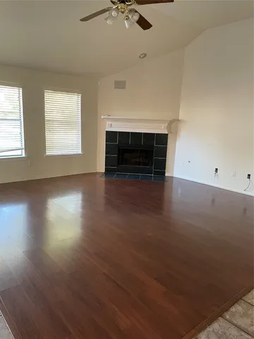 an empty room with wooden floor fireplace and windows