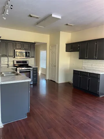 a kitchen with stainless steel appliances wooden floors and wooden cabinets
