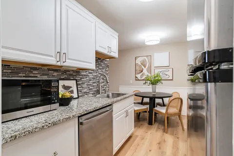 a kitchen with stainless steel appliances granite countertop a stove a sink and a microwave