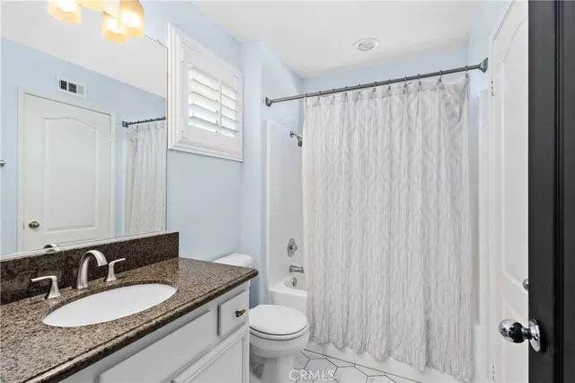 a bathroom with a granite countertop sink toilet and a mirror