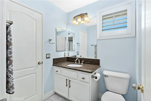 a bathroom with a granite countertop sink and a toilet