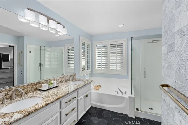 a bathroom with a granite countertop sink a mirror a bathtub and next to a window
