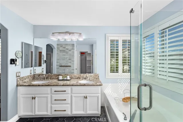 a bathroom with a granite countertop sink a large mirror and a bathtub