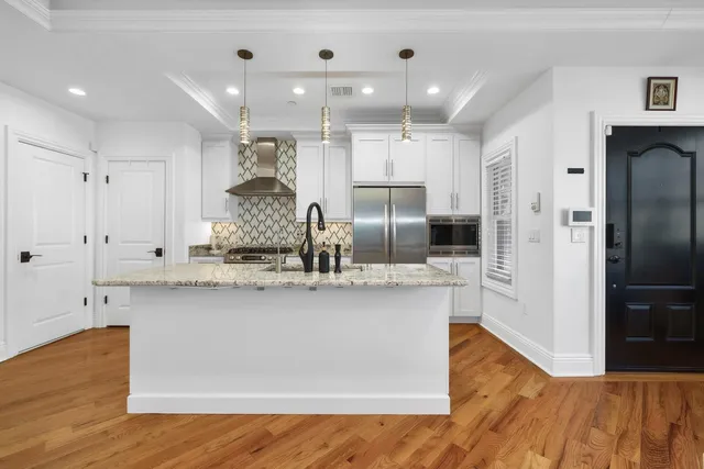 a large kitchen with stainless steel appliances a large counter top a stove and a refrigerator