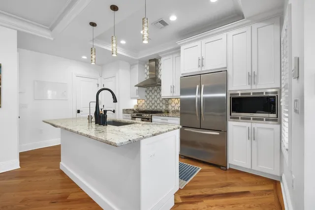 a kitchen with kitchen island granite countertop a sink stainless steel appliances and white cabinets