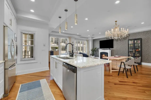 a kitchen with kitchen island granite countertop a stove oven and a view of dining hall with wooden floor