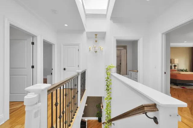 a view of a hallway to a livingroom with wooden floor and furniture