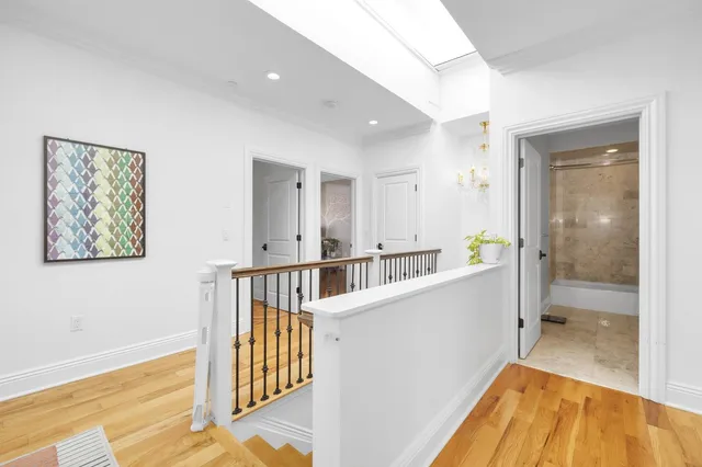 a view of a hallway with wooden floor and a bathroom