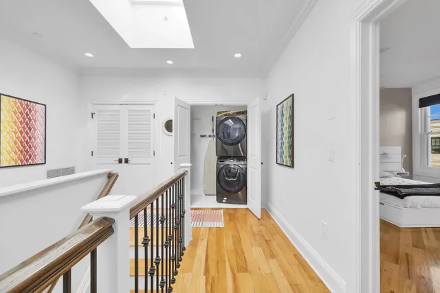 a view of hallway with window and wooden floor