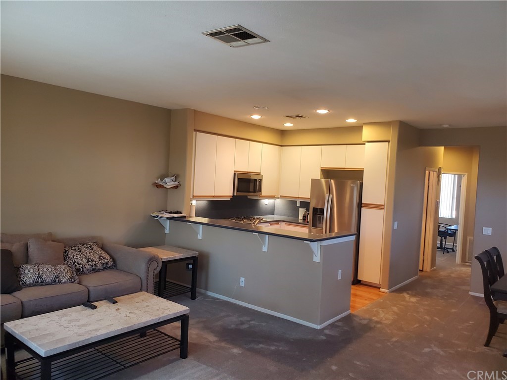 a living room with stainless steel appliances kitchen island granite countertop furniture and a refrigerator