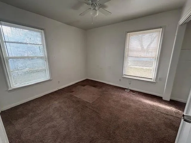 an empty room with a window and a ceiling fan