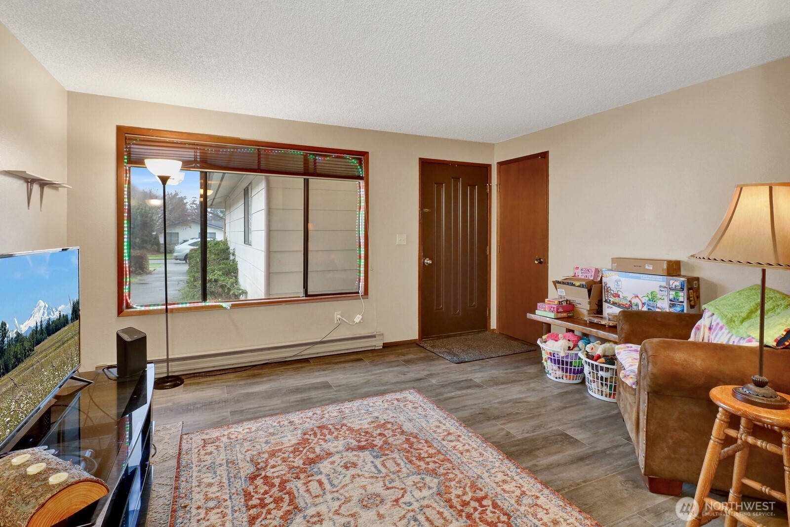 908 Liberty Street Lynden, WA 98264 - Photo 21 of 27 a living room with furniture a flat screen tv and a large window