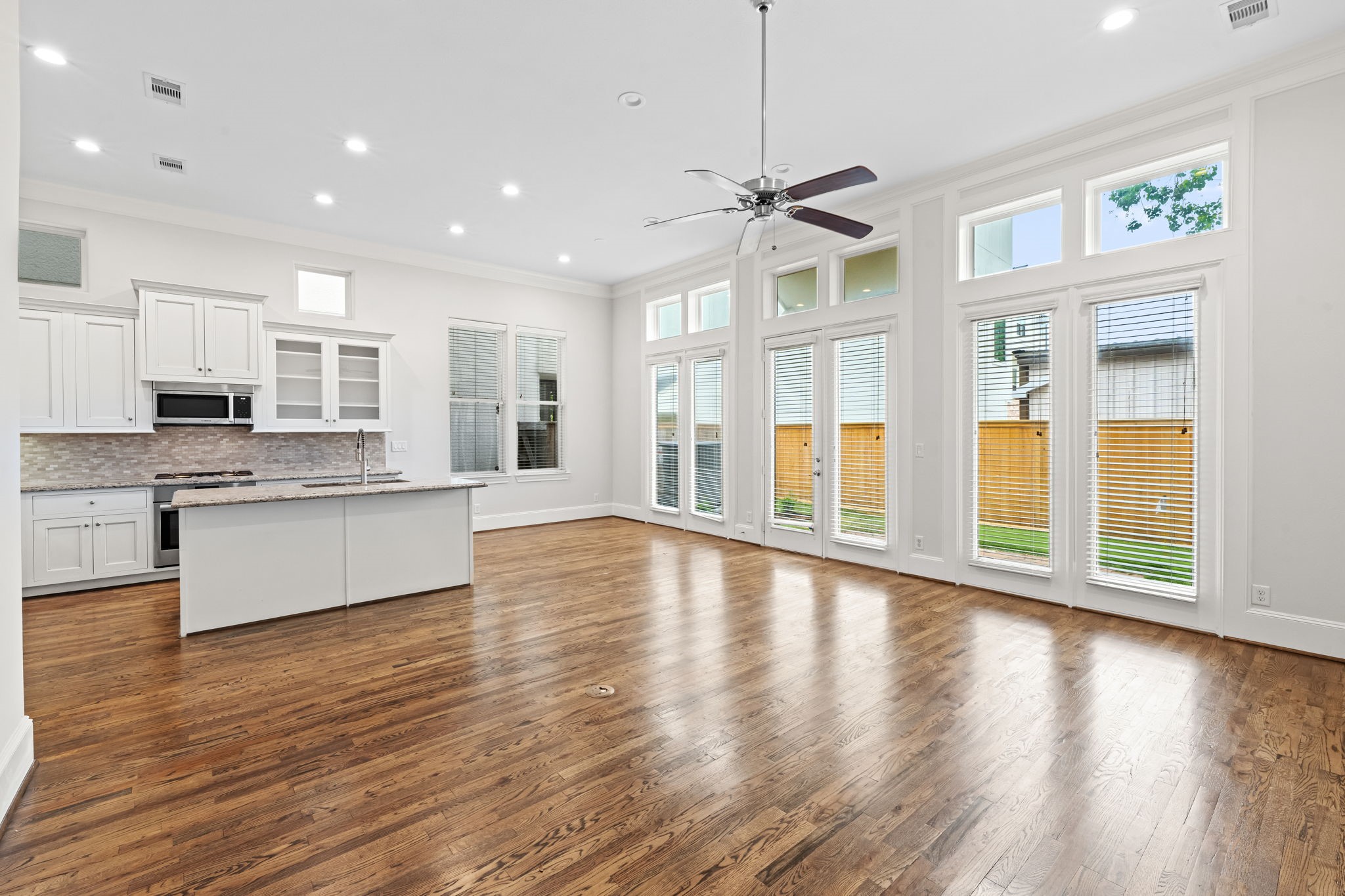 5621 Cohn Meadow Lane Houston, TX 77007 - Photo 4 of 35 Light-filled first-floor living space with soaring ceilings, rich hardwood floors, and seamless open-concept design connecting the kitchen and dining areas.