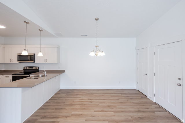 693 West 4500th South, Unit O304 Mapleton, UT 84664 - Photo 13 of 16 Kitchen with light wood-style floors, white cabinets, a peninsula, stainless steel appliances, and suspended lighting