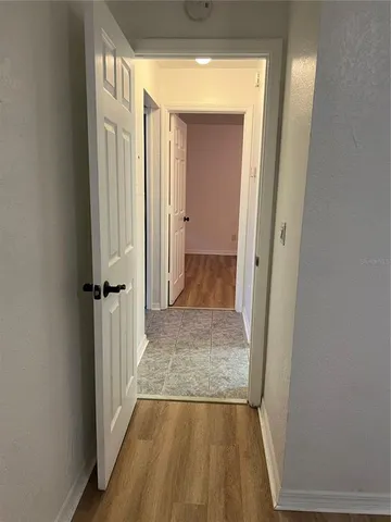 a view of a hallway with wooden floor and a bathroom