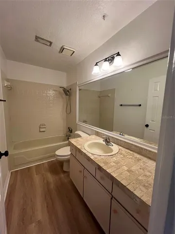 a bathroom with a granite countertop sink a toilet and shower