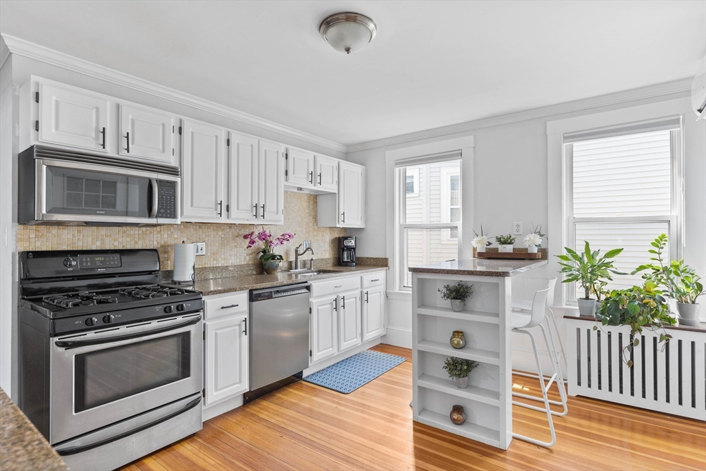 108 King Street, Unit THREE Boston, MA 02122 - Photo 7 of 18 a kitchen with granite countertop a sink cabinets stainless steel appliances and a window
