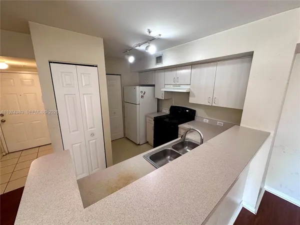 a living room with stainless steel appliances furniture a refrigerator and cabinets