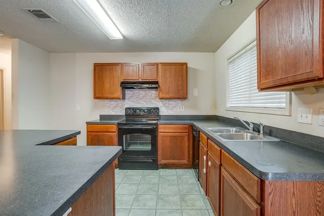 a kitchen with stainless steel appliances granite countertop a sink a stove top oven a counter space and cabinets