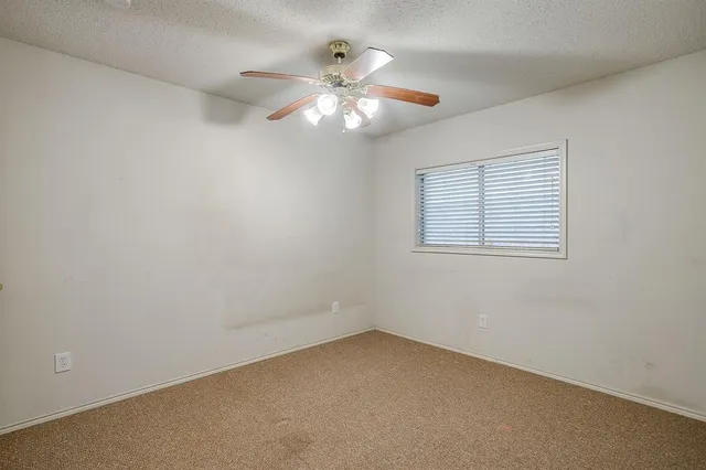an empty room with a window and a fan