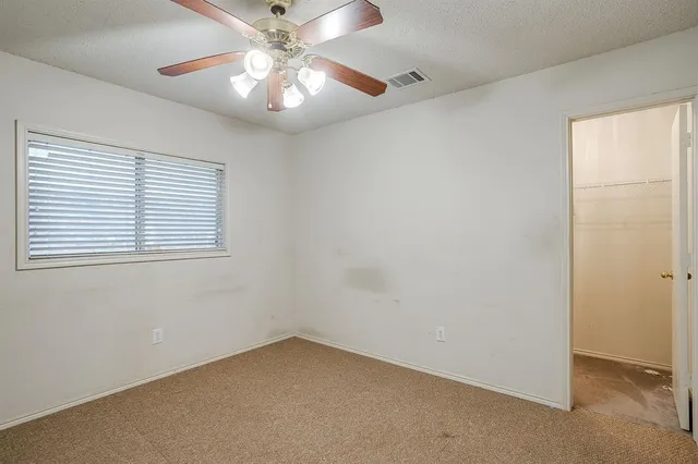 an empty room with a chandelier fan and windows