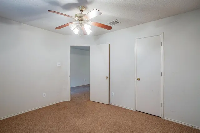 an empty room with a window and a fan