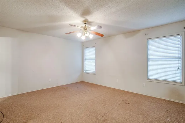 an empty room with windows and fan