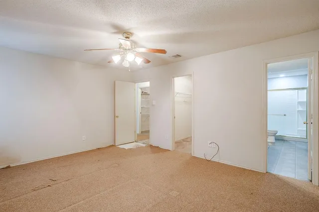 en empty room with windows and chandelier fan
