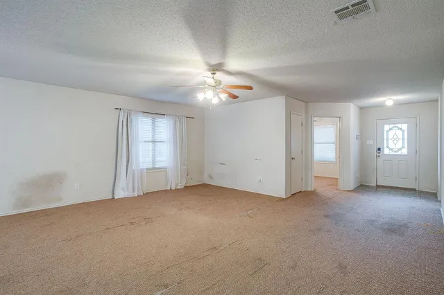 an empty room with windows and chandelier fan